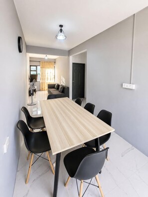A modern dining area with a rectangular table, black chairs, and a light-colored floor. - 2-bed Apartment in Mont Choisy Grand Baie (Trou aux Biches)
