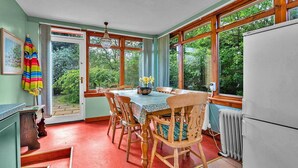 Een eetgedeelte met een tafel voor vier personen, omringd door houten stoelen. Een raam biedt uitzicht op groen buiten.