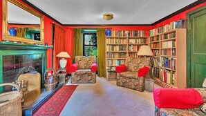 Een gezellige woonkamer met een open haard, een boekenkast en een gestreept fauteuil.