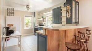 Eine Küche mit einer Holzeinsel, Barhocker, einem weißen Kühlschrank und einem Deckenventilator.