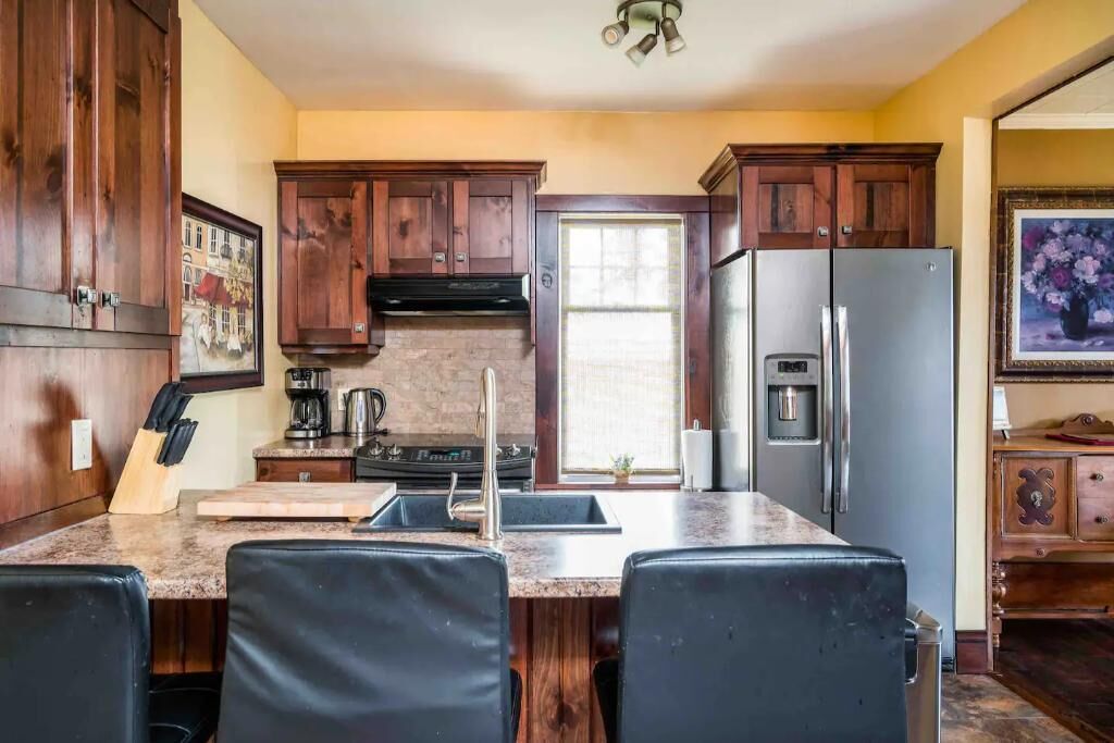 A kitchen with wooden cabinets, a stainless steel refrigerator, a gas stove, and a sink.