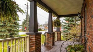 A covered porch with brick pillars, a white railing, and potted plants. - JJ’s small town country retreat     (Badjeros)