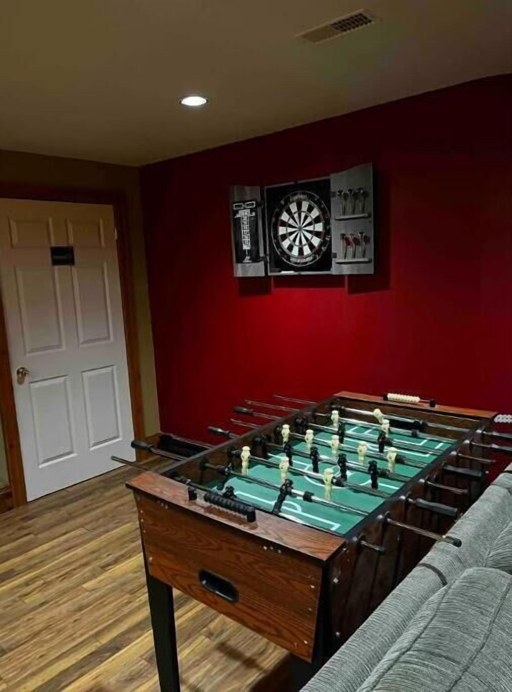 Una habitación con mesa de futbolín, dardos y una puerta.
