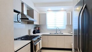 A modern kitchen with a stove, oven, sink, and refrigerator.