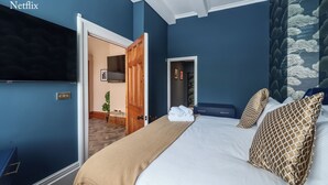 Ein großes Bett mit Fernseher, eine Holztür und eine blaue Wand.