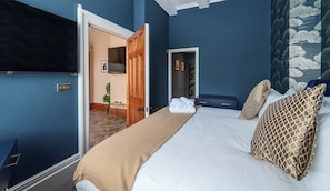 Un grand lit avec un téléviseur, une porte en bois et un mur bleu.