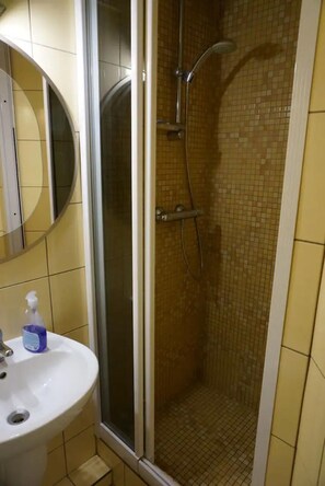 A bathroom with a white sink, a mirror, and a shower with a tiled wall.