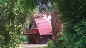 A rustic cabin with a red roof, surrounded by dense greenery. - Cottage in the Picturesque Beskid Maly Mountains (Porabka)