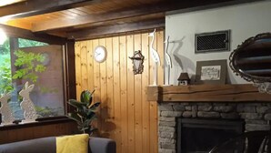 A cozy living room with a stone fireplace, wooden walls, a sofa, and a chair. - Cottage in the Picturesque Beskid Maly Mountains (Porabka)
