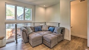 Un salon d’angle avec un canapé d’angle, de grandes fenêtres et une vue sur l’extérieur.