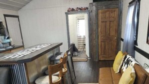 A compact living space with a kitchenette, a dining area with wooden chairs, a brown sofa with cushions, and a wooden door leading to another room. - Rising Wolf Cabin
Glacier National Park
Centralized location for exploring (East Glacier Park)