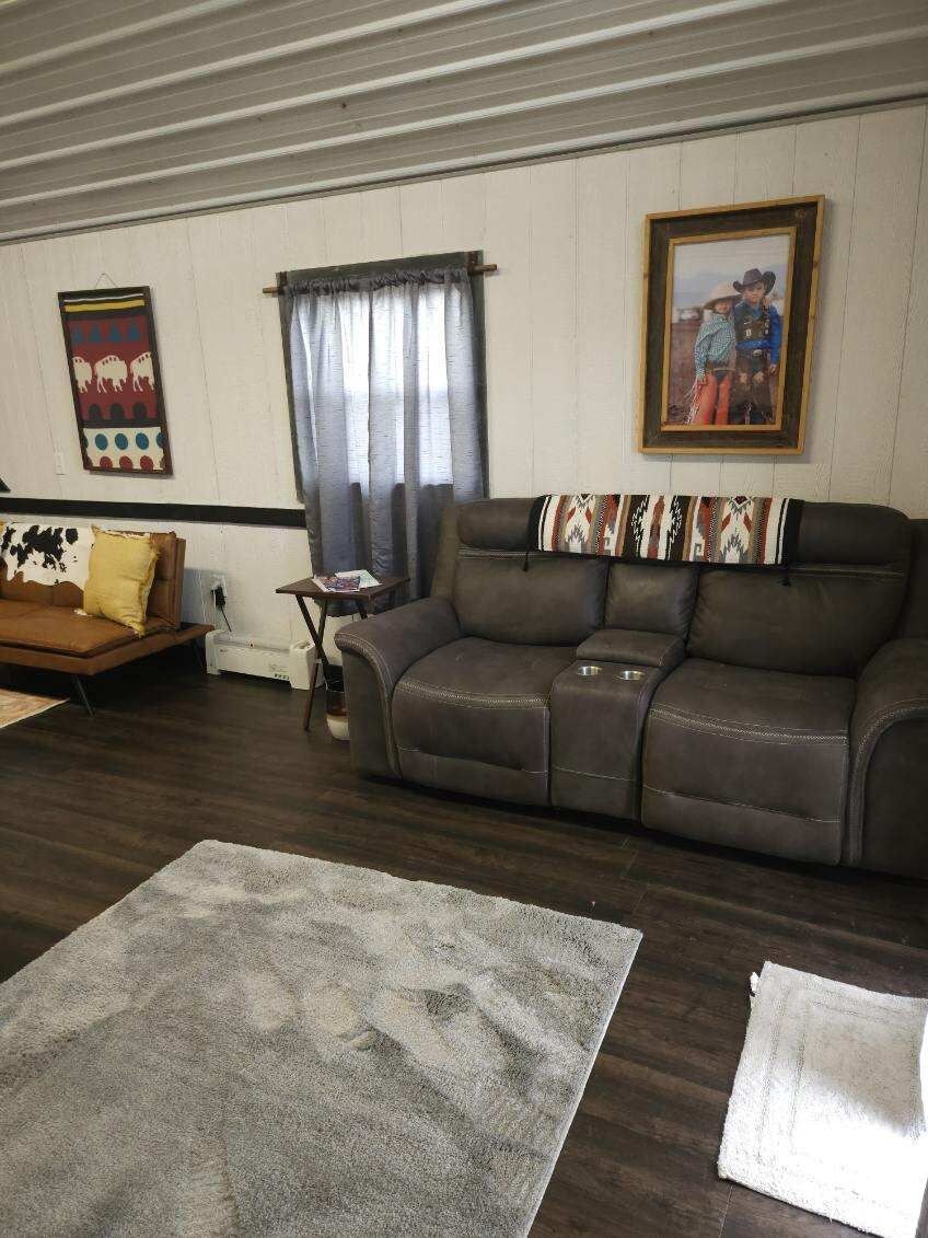 A living room with a brown leather sofa, a patterned rug, a small table with a lamp, and a framed picture on the wall.