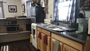 A kitchen with wooden cabinets, a stove, a microwave, and a coffee station. - Rising Wolf Cabin
Glacier National Park
Centralized location for exploring (East Glacier Park)