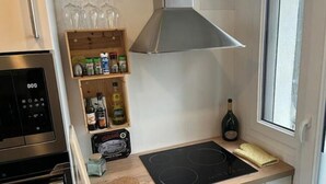 Eine moderne Küche mit Einbauofen, Kochfeld, einer Weinflasche und einem Regal mit verschiedenen Gewürzen.