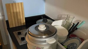 A kitchen with a rice cooker, a cutting board, a glass, and a dish rack. - Grass Residence T3 34th Floor (Quezon City)