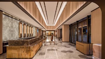 Un hall d’hôtel doté d’un comptoir d’accueil, d’une cloison en verre et d’un design moderne.
