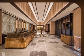 A hotel lobby with a reception desk, a glass partition, and a modern design.