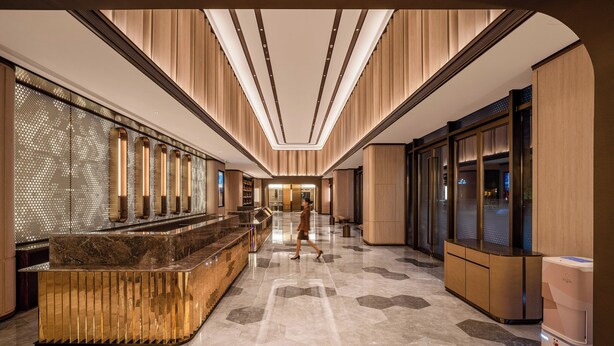 Un hall d’hôtel doté d’un comptoir d’accueil, d’une cloison en verre et d’un design moderne.
