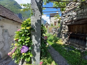 A narrow stone pathway leading to traditional stone buildings with a mountain backdrop.
