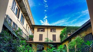 Un patio con un sendero adoquinado, plantas en macetas y un edificio con tejado de baldosas.