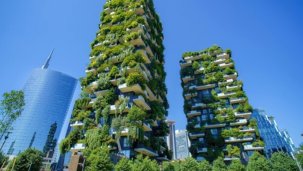 Un edificio alto con múltiples balcones cubiertos de vegetación.