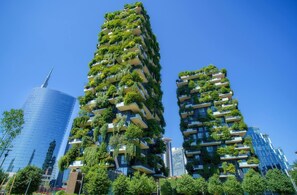Un edificio alto con múltiples balcones cubiertos de vegetación.