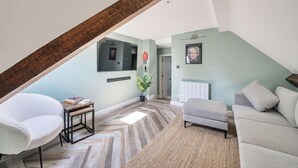 A cozy living room with a herringbone floor, a white armchair, a grey sofa, and a wooden coffee table. - 3 Bed Cosy Loft Space Apartment - Free On-Site Parking (Bowness-on-Windermere)