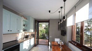 Eine Küche mit hellblauen Schränken, einem Holzespeisebereich und Blick auf einen Balkon mit einem Haus im Hintergrund.