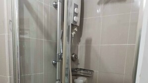 A glass-enclosed shower stall with a control panel, a towel rack, and a small shelf. - Grass Residence Tower ii 2011 (Quezon City)