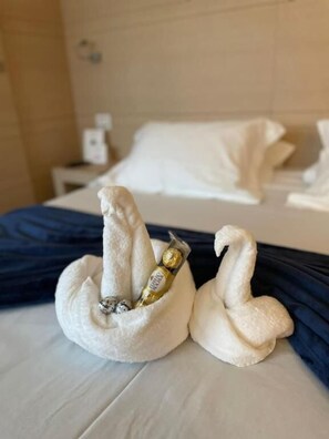 Een hotelkamer met een net opgemaakt bed, een nachtkastje met een lamp, en een wandcontactdoos.