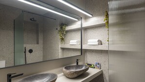 A modern bathroom with a large mirror, two stone sinks, and a shower visible in the reflection. - Hoppersgr- Amazing apt in the heart of Athens - 1
 (Athina)