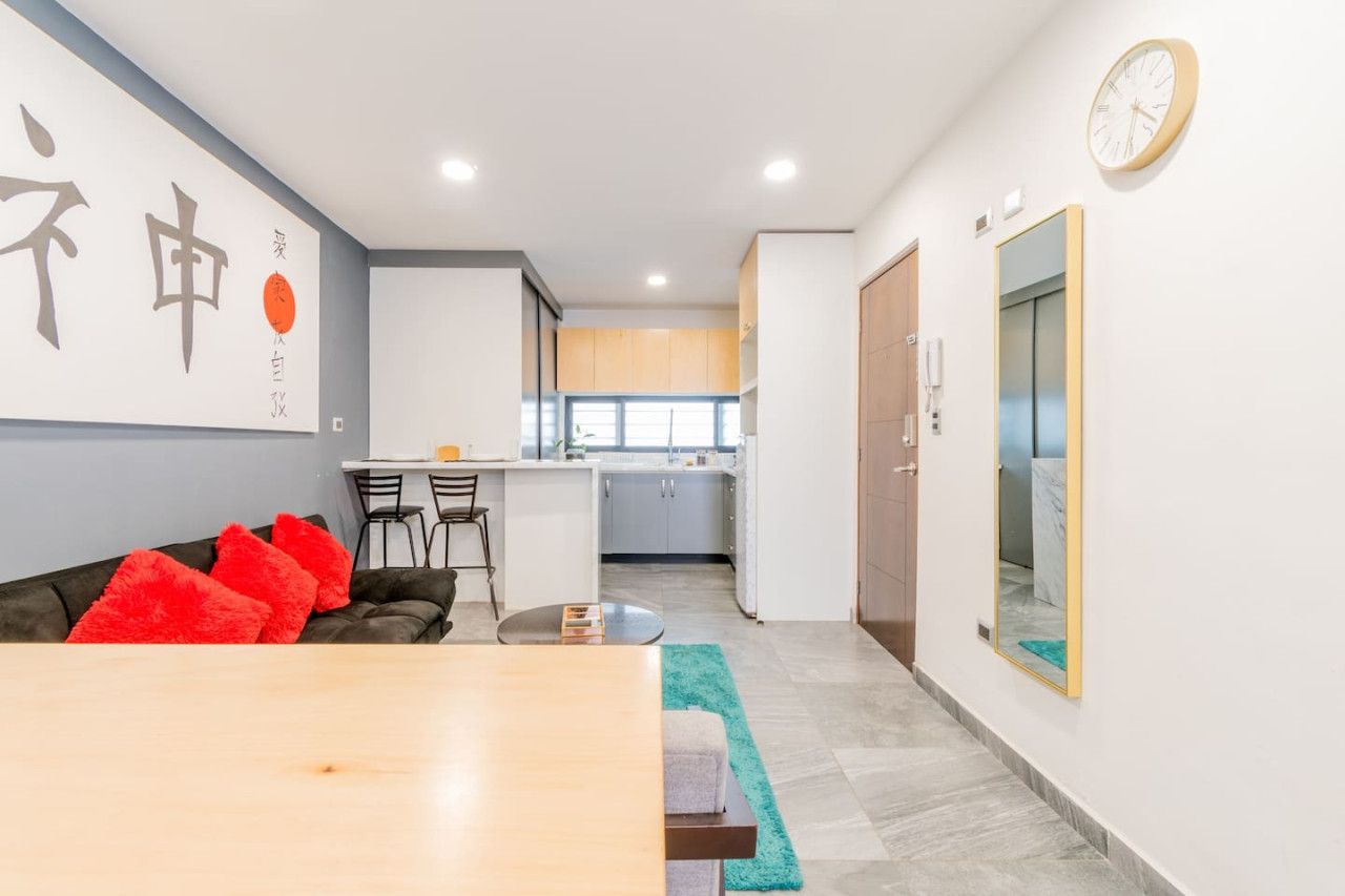 A modern living space with a dining area, kitchen, and a large mirror.