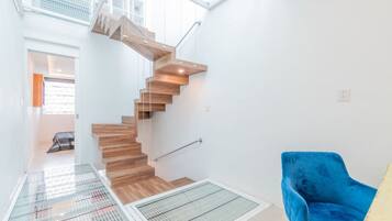 A modern interior with a wooden staircase, a blue chair, and a glass ceiling.