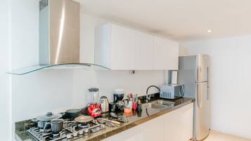 A modern kitchen with stainless steel appliances, a glass shelf, and white cabinetry.