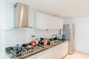 Una cocina moderna con electrodomésticos de acero inoxidable, un estante de vidrio y armarios blancos.