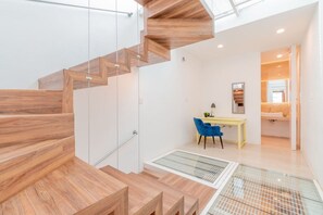 A modern interior with a wooden staircase, a desk with a chair, and a bathroom with a sink. - LOFT ULTRA Moderno y Minimalista | Cama KING Size (Durango)