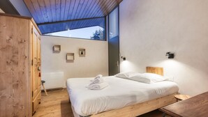 Een moderne slaapkamer met een houten bed, een houten garderobe en een dakraam.