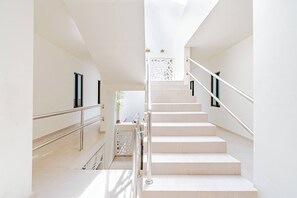 En moderne trappe med metalgelændere, hvide vægge og et geometrisk design øverst.