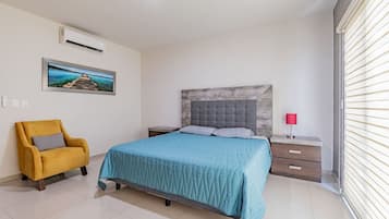 A bedroom with a bed, a nightstand, a chair, a picture on the wall, and a window with blinds.