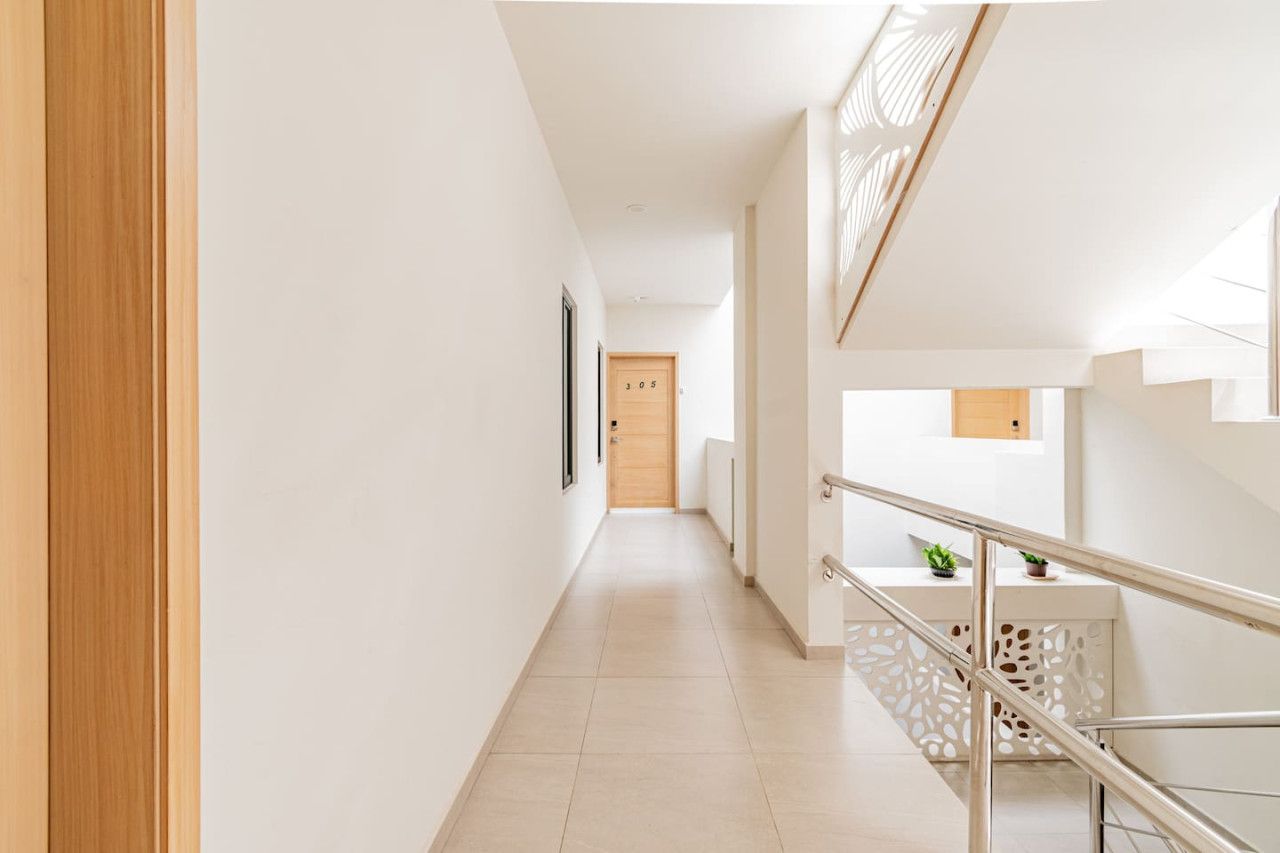 Ein moderner Flur mit einer Holztür, einer Treppe mit Geländer und einer kleinen Pflanze auf der Landung.