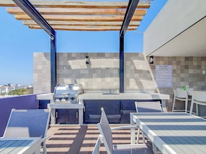 Un patio exterior con una parrilla, asientos y un muro decorado.