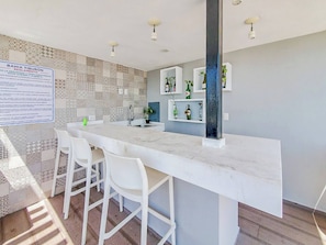 A modern kitchen with a marble countertop, white bar stools, and a patterned backsplash. - Lujoso Condominio Tiburon a 3 Cuadras de la Playa (Mazatlán)