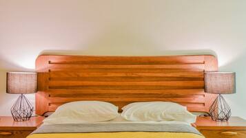 A bed with a wooden headboard, two bedside lamps, and a bedside table.