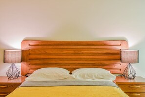 Un letto con una testiera in legno, due lampade sui comodini e un tavolino da notte.