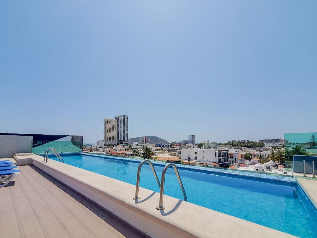 A rooftop pool with clear blue water, a cityscape view, and a modern building in the background.