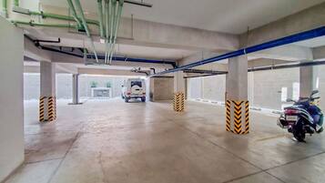 A parking garage with concrete floors, pillars, and blue pipes.