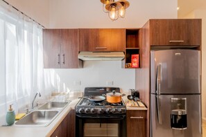 A modern kitchen with a stove, oven, refrigerator, and a coffee maker.