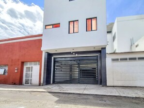 En moderne bygning med garageindgang, nummer 143, og en rød bygning ved siden af.