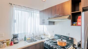 A compact kitchen with a stove, sink, and wooden cabinets.