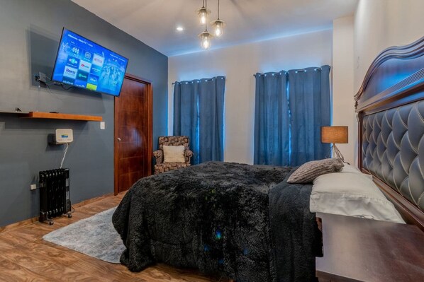 A bedroom with a bed, a TV mounted on the wall, and a radiator.